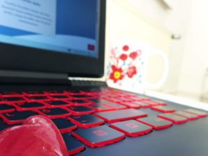Ein Herz für Website-Marketing. Du siehst einen Laptop mit Fokus auf die Tastatur. Links im Vordergrund befindet sich ein Herz, im Hintergrund eine Tasse.